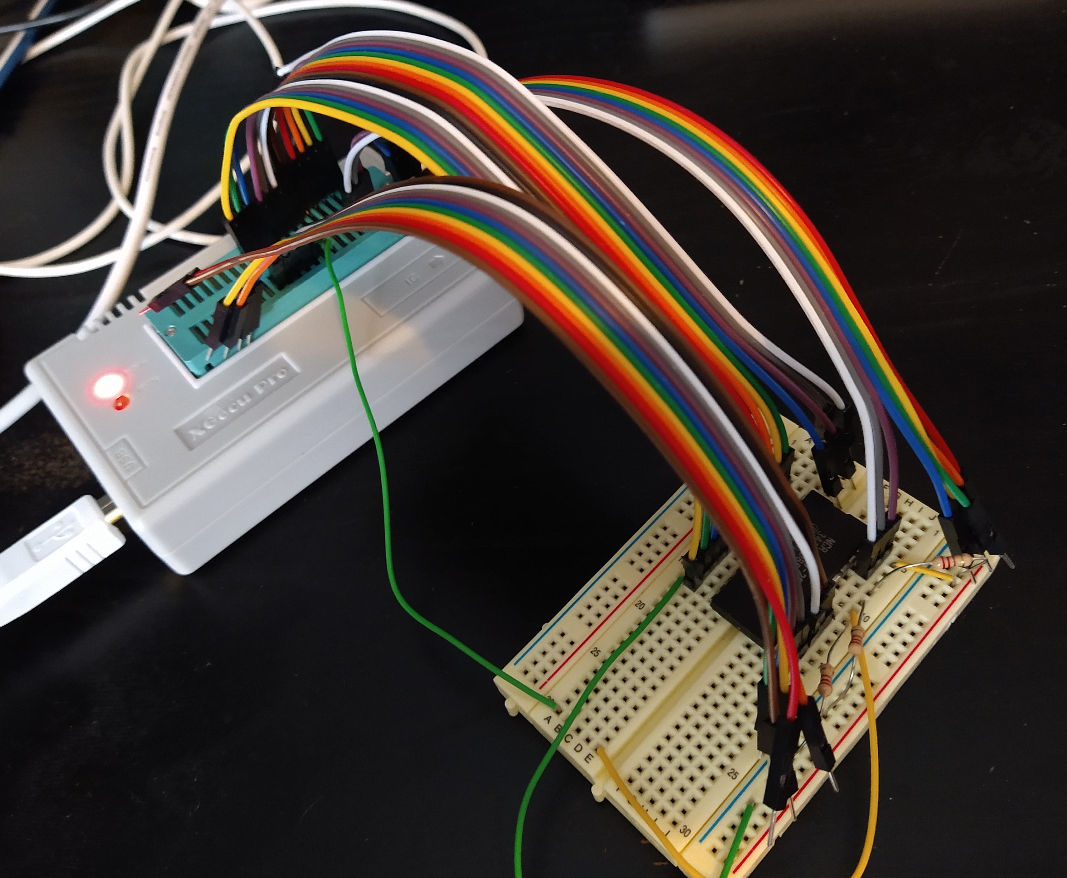 An IC chip on a breadboard, connected by many wires to a chip reading device